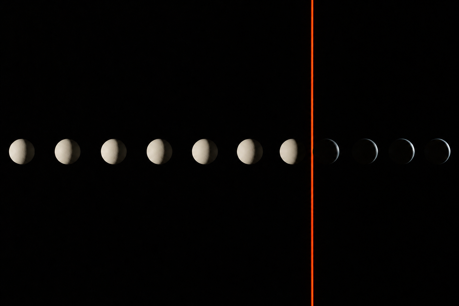 A stroboscopic photograph of eleven identical spheres frozen in flight across a black field. A thin vermilion plane of light cuts the frame near the right. The spheres before the plane are brightly lit; the ones past it have fallen into shadow.